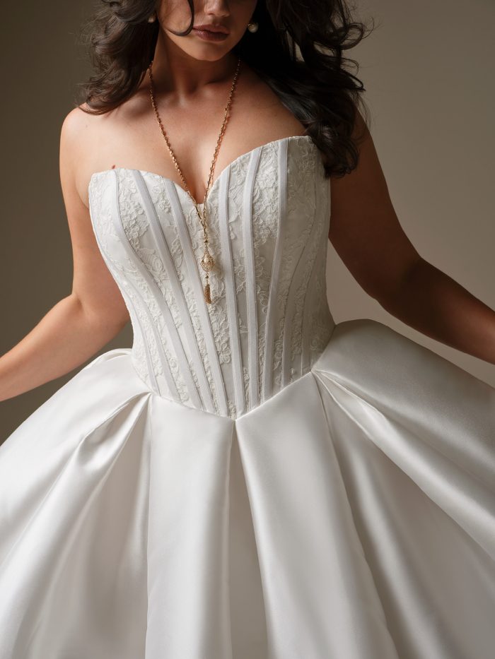 Close-up of Ashland by Maggie Sottero — strapless ballgown wedding dress featuring structured corsetry, lace details, and voluminous satin pleats, highlighting the gown’s flattering curve fit.
