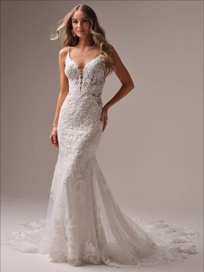 Bride wearing the Bianca fit-and-flare wedding dress featuring beaded and sequin lace motifs over glitter tulle, a plunging illusion V-neckline, and an extended scalloped lace train for a glamorous, romantic look.