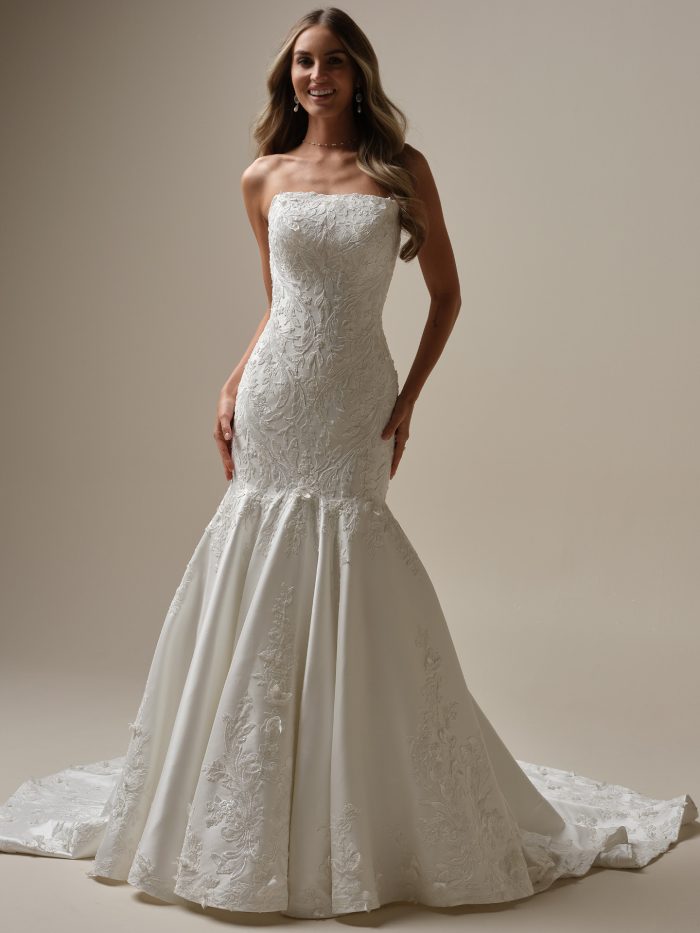 Strapless fit-and-flare wedding dress Delanie by Maggie Sottero featuring an embroidered lace bodice, straight neckline, and flared skirt with lace appliqués.