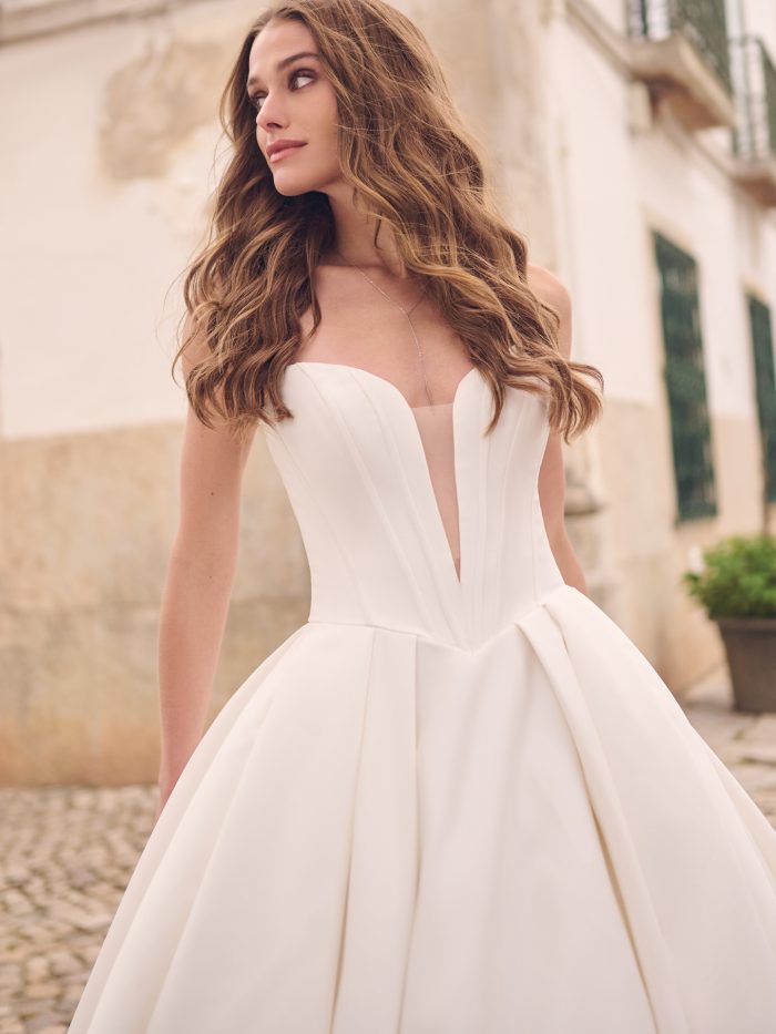 Close-up of Derrick by Maggie Sottero — chic strapless Mikado ballgown with illusion plunge neckline and corset-inspired bodice detailing.