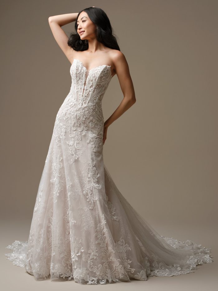Bride wearing Farrah by Maggie Sottero, a strapless lace fit-and-flare wedding dress with a deep illusion neckline, exposed boning, and floral lace motifs.