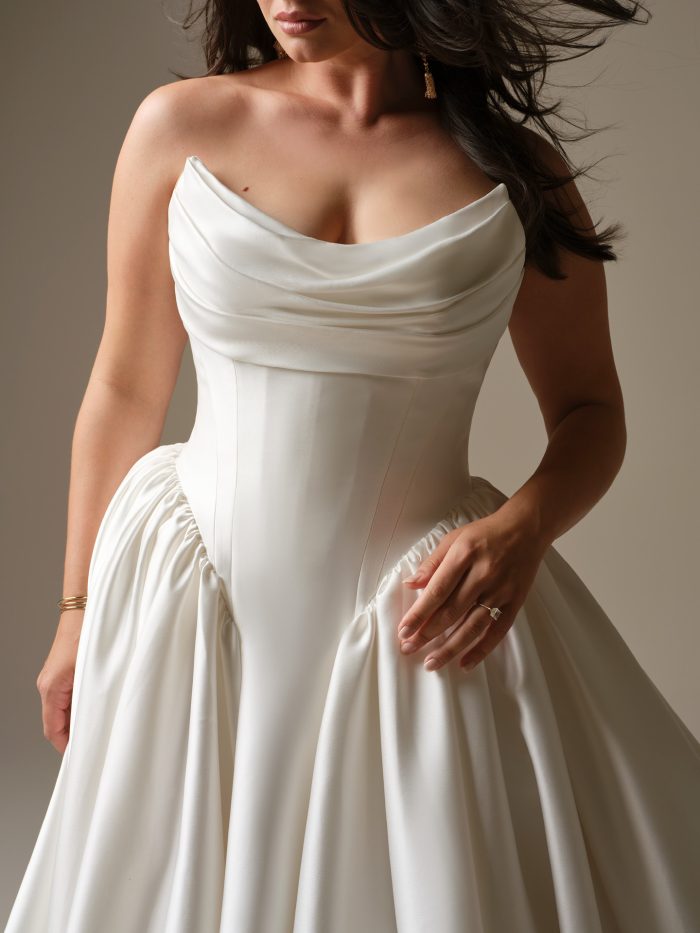 A close-up of the Maggie Sottero Hudson wedding dress highlighting the draped satin neckline, structured bodice, and gathered satin skirt.