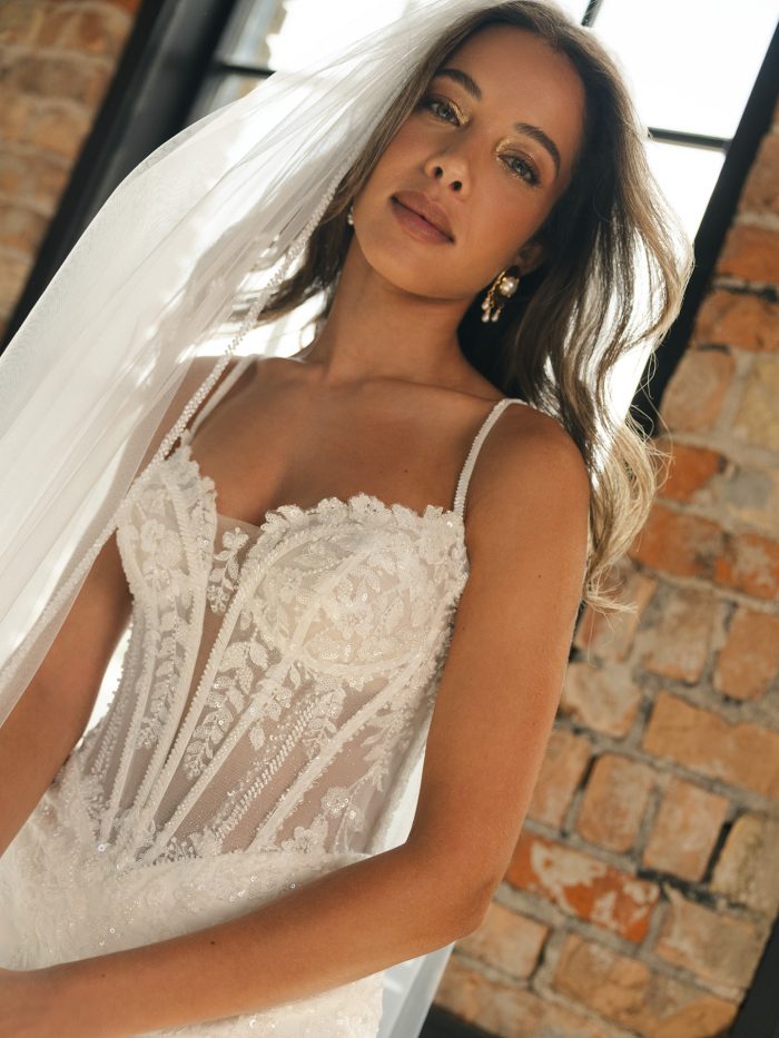 Close-up of India by Maggie Sottero, featuring a beaded lace bodice with illusion corset details, spaghetti straps, and a deep neckline.