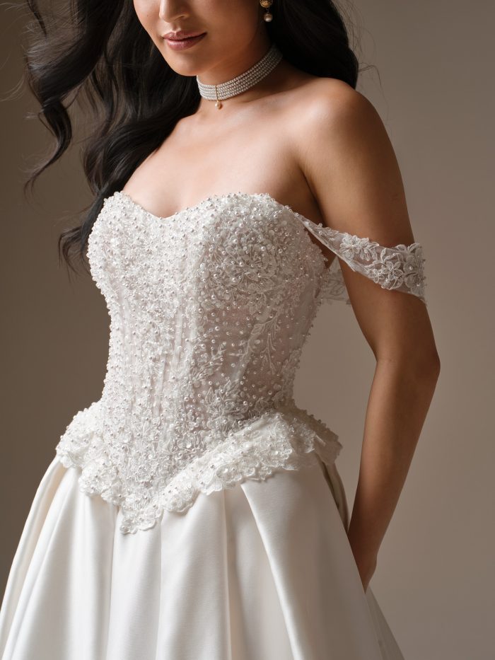 Close-up of the London wedding dress by Maggie Sottero showcasing a strapless sweetheart bodice adorned with delicate pearl beading and lace details.