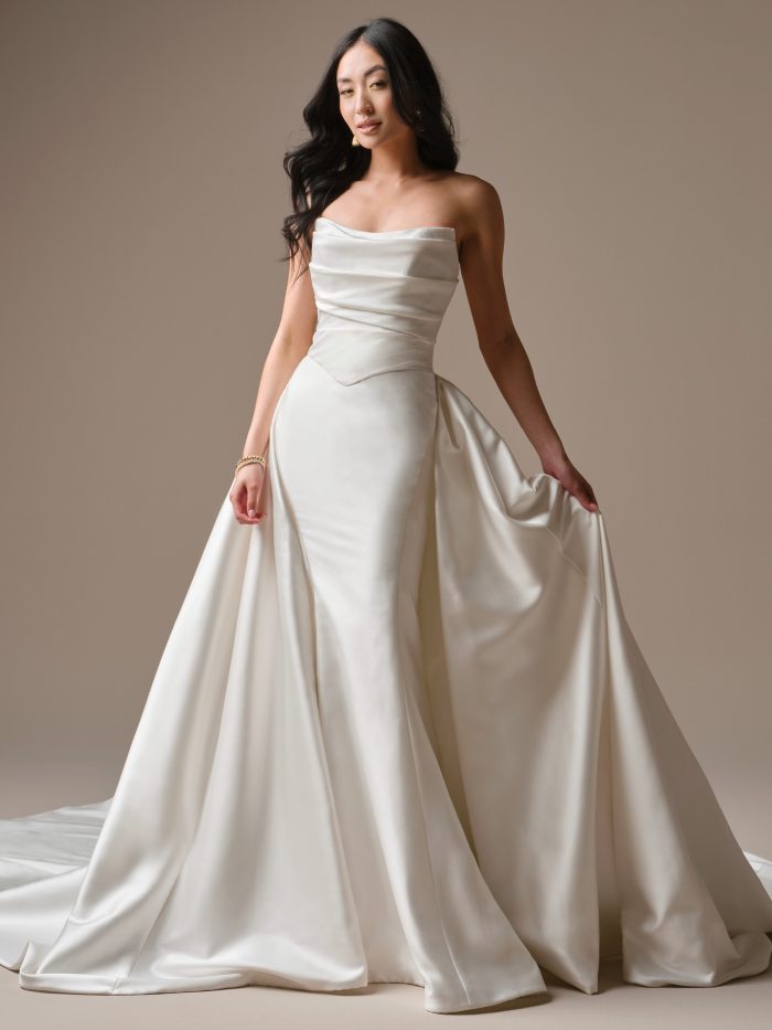 Maureen Lane by Maggie Sottero satin fit-and-flare wedding dress with a softly draped strapless bodice, angled waist detail, and flowing skirt