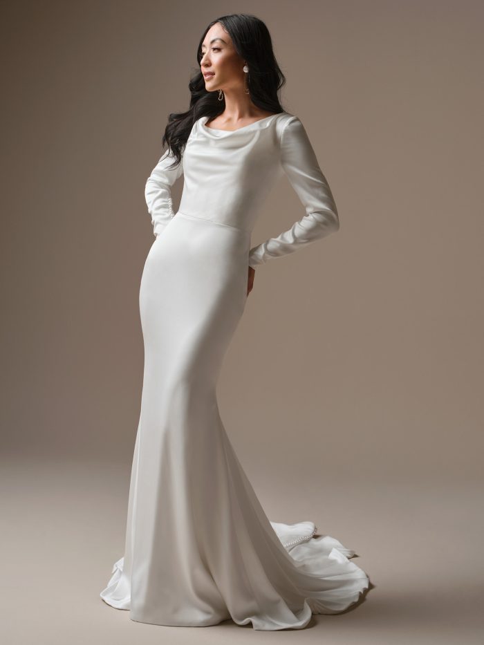 Melinda satin sheath wedding dress featuring a soft cowl neckline, long fitted sleeves with pearl button cuffs, and sleek elongated silhouette.