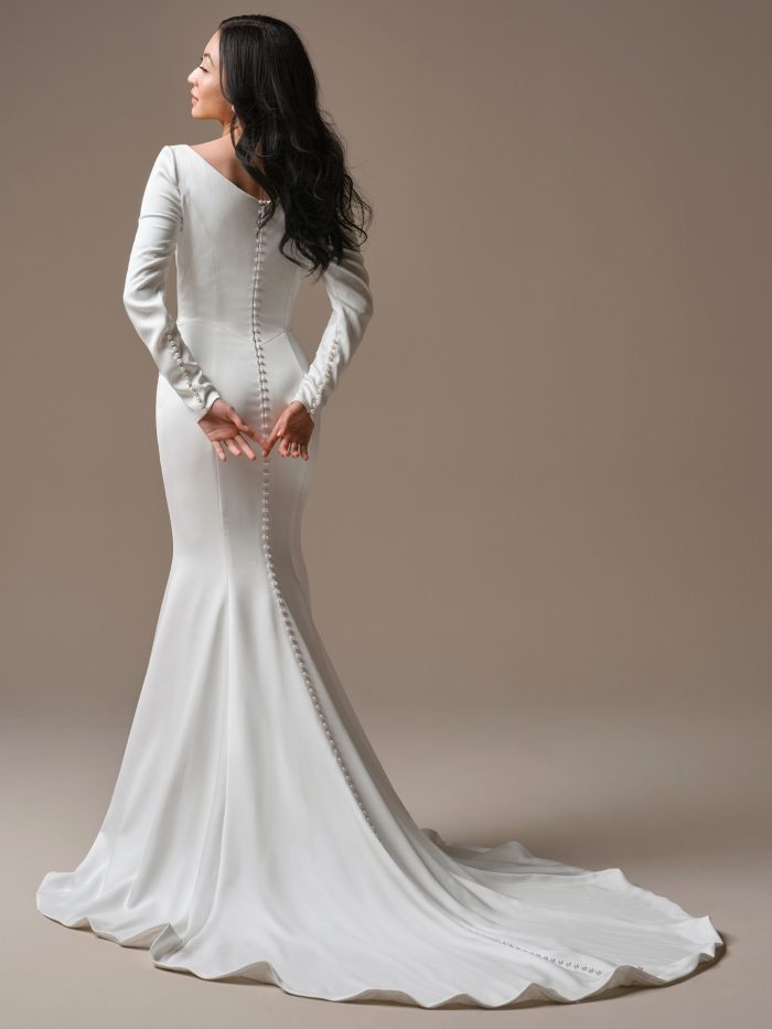 Back view of Melissa by Maggie Sottero, satin sheath bridal gown with soft V-back, pearl button closure, and flowing train.