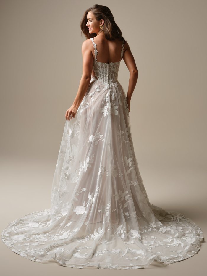 Back view of the Natalie Marie A-line wedding dress showcasing a lace bodice, sheer side details, floral appliqués, and a soft tulle skirt with an illusion lace train.
