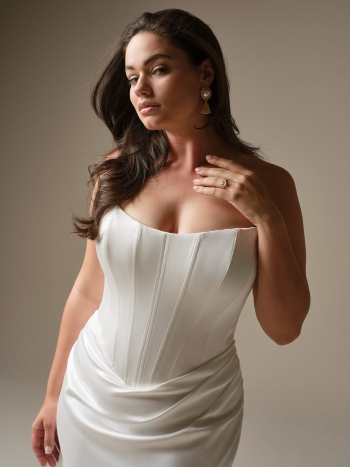 Close-up of Sinclaire by Maggie Sottero featuring a structured strapless corset bodice, smooth satin fabric, and elegant draping at the waist