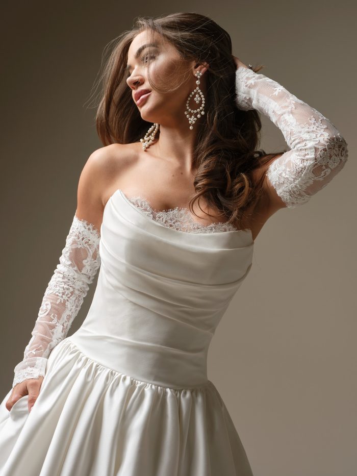 Close-up of the Sylvana wedding dress showing the draped strapless neckline, lace sleeves, and smooth fitted bodice.