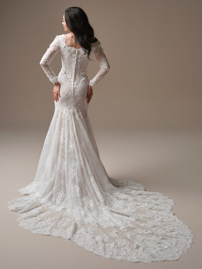 Back view of the Takera Leigh fit-and-flare wedding dress featuring a modest V-back, covered buttons, long illusion lace sleeves, and an extended scalloped Chantilly lace train.