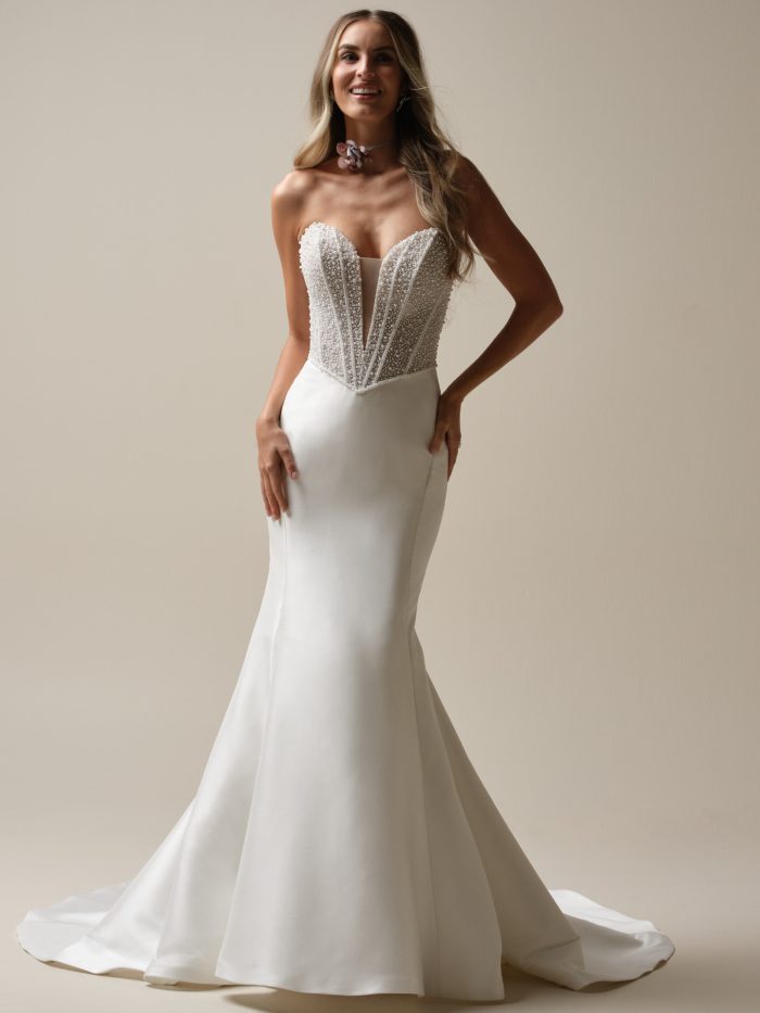 Bride wearing the Maggie Sottero Tina Marie fit-and-flare wedding dress featuring a strapless plunging neckline, pearl-encrusted corset bodice, and sleek satin skirt with a chapel-length train.