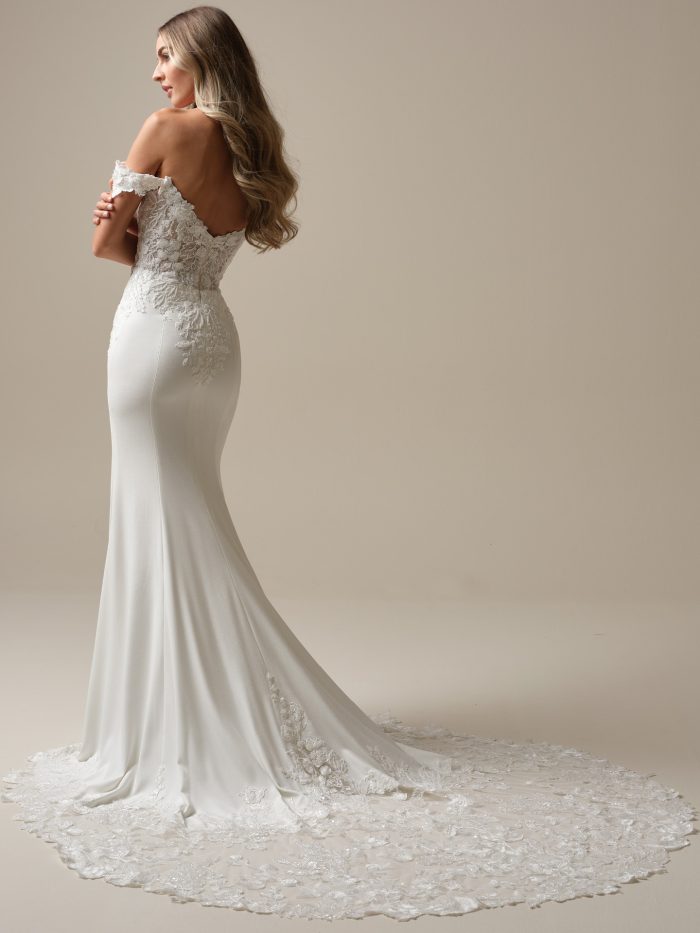 Back view of the Adeline gown showing the lace-detailed illusion bodice, soft crepe skirt, and chapel-length train adorned with floral lace appliqués.