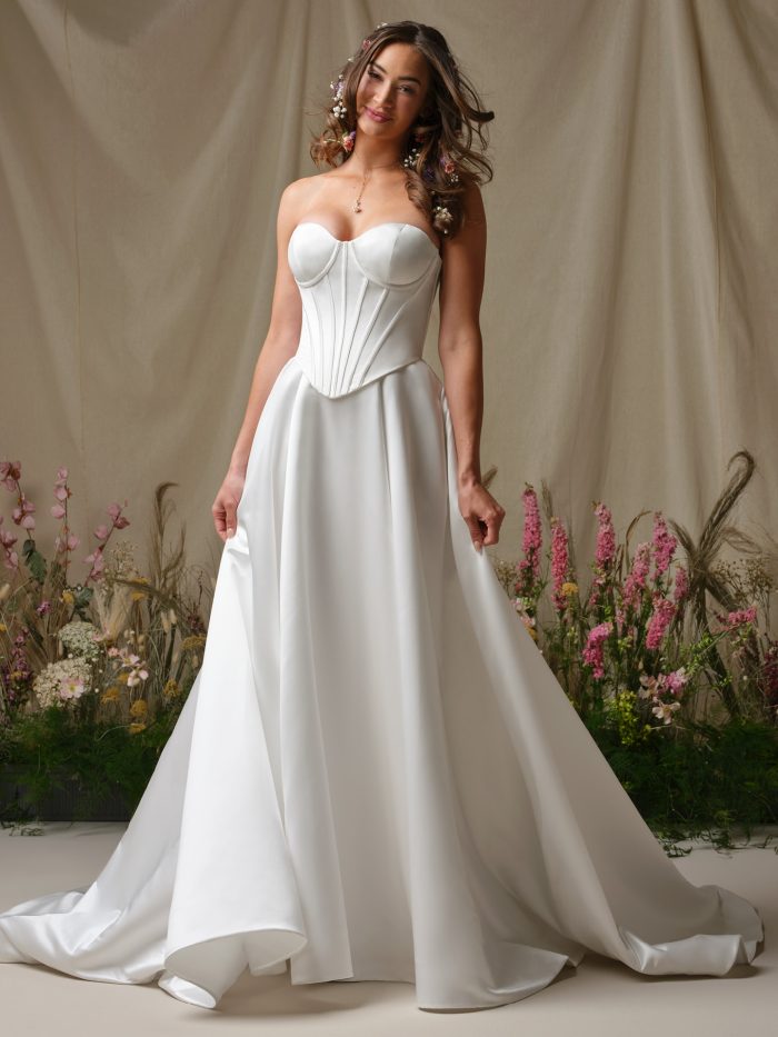 Front view of the Alexia wedding dress featuring a strapless structured mock two-piece bodice and a full A-line skirt with soft drape and movement.
