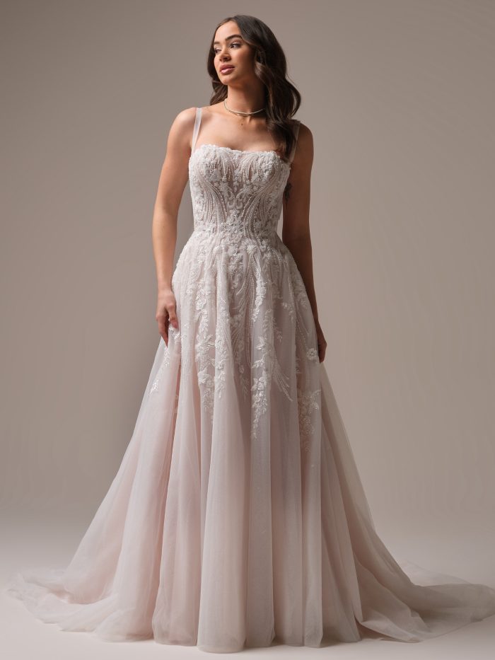 Bride wearing the Rebecca Ingram Angie A-line wedding dress featuring a beaded lace sweetheart bodice with delicate spaghetti straps and a soft blush tulle skirt.