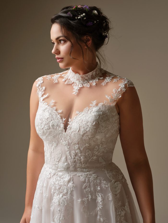 Close up of the Cody wedding dress showing the mock illusion turtleneck, sheer sequined lace bodice, illusion cap sleeves, and delicate lace detailing.
