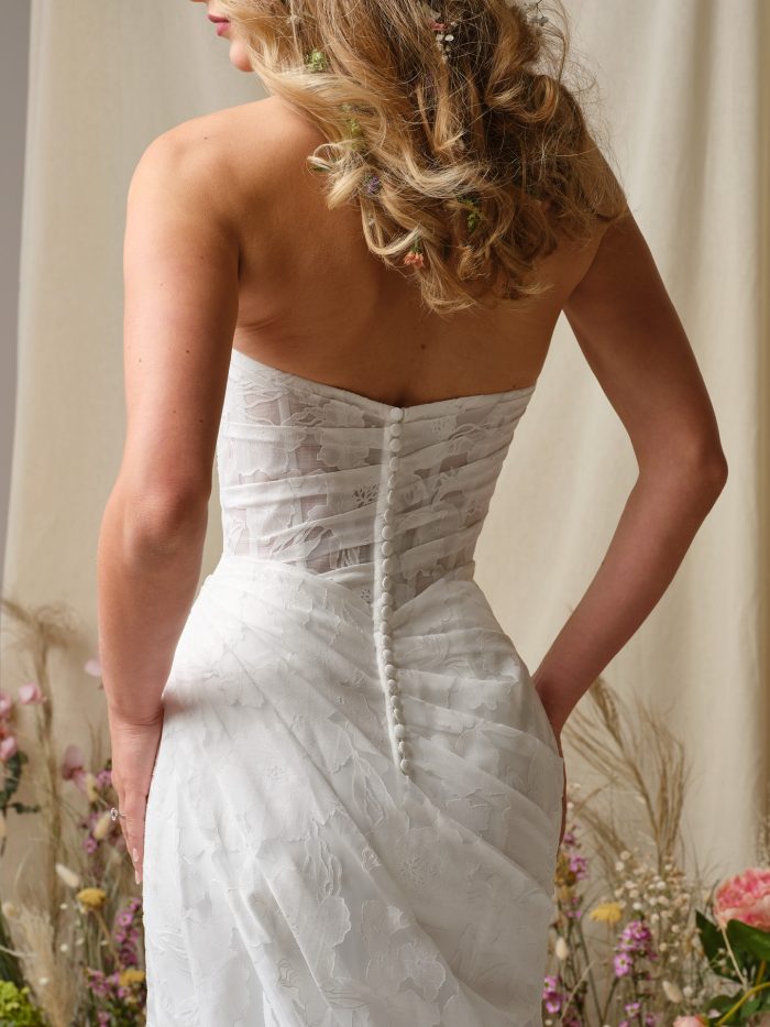 Back view of the Kendall wedding dress highlighting the strapless neckline, ruched printed organza, covered button closure, and flattering hourglass fit.