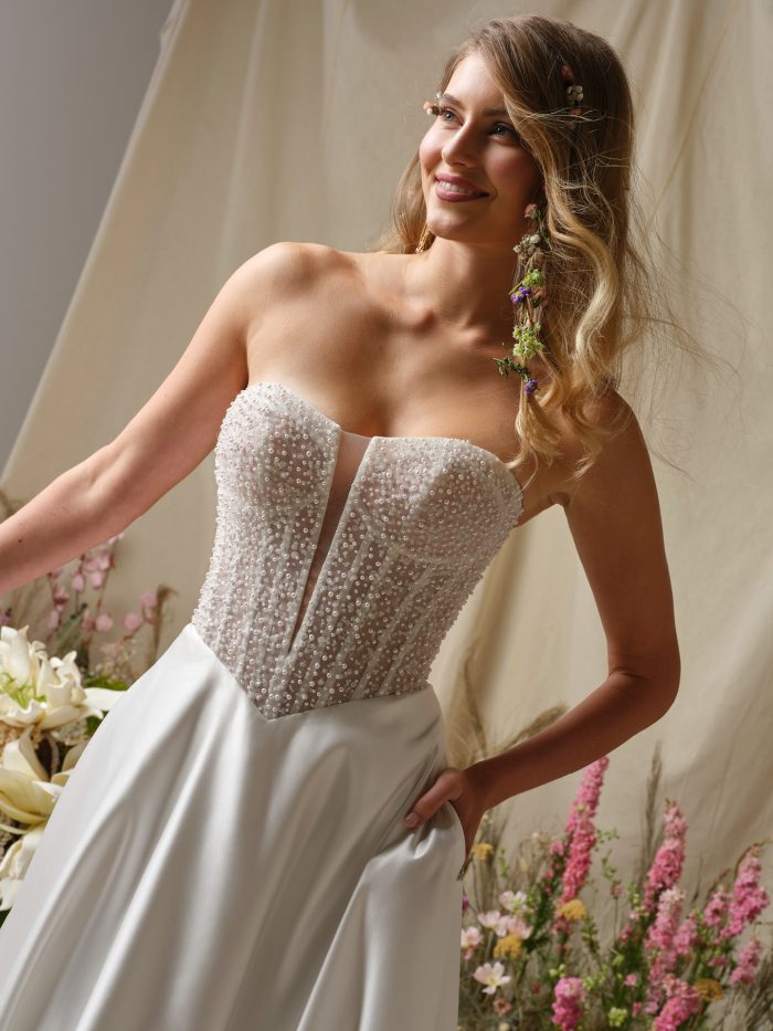 Close-up of the Marty wedding dress by Rebecca Ingram showcasing the intricately beaded strapless bodice, sheer plunge inset, and structured corset detailing.