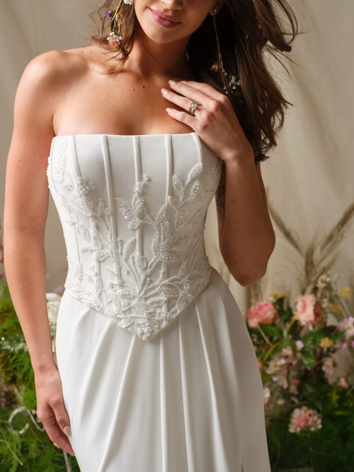 Close-up of Terry by Rebecca Ingram, featuring a strapless straight-across neckline and beaded lace embroidery on a structured corset bodice.
