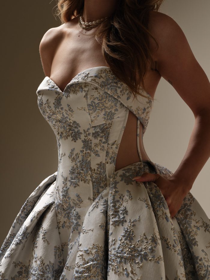 Close up of the Aberdeen wedding dress showing the sweetheart neckline, corseted bodice, and intricate blue and gold floral brocade fabric with side illusion detailing.