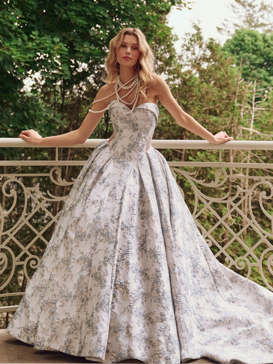 Bride standing against a hand rail wearing a colorful ballgown wedding dress