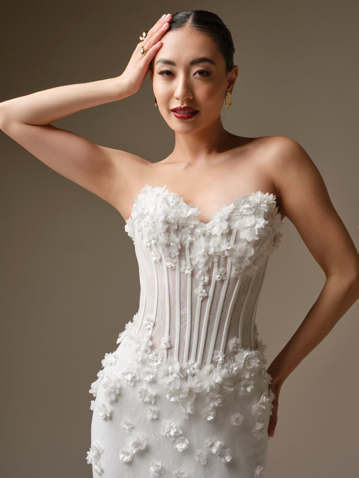 Close-up of the Akari strapless corset wedding dress by Sottero and Midgley, showcasing exposed boning and three-dimensional floral appliqués across the bodice.