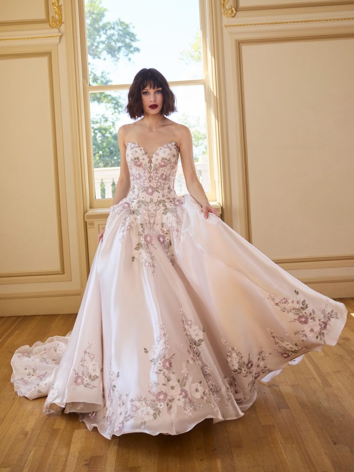 Bride wearing Alvarez by Sottero and Midgley, a strapless ball gown wedding dress with a sweetheart neckline and multicolored floral embroidery over blush satin.