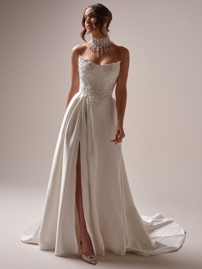 Bride wearing the Sottero and Midgley Amadora A-line wedding dress featuring a strapless neckline, structured satin bodice with embroidered sequin lace appliqués, and a sleek skirt with a high slit for modern drama.