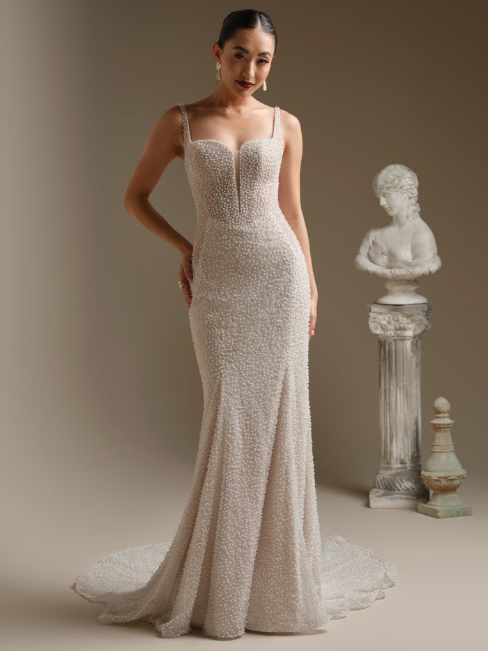 Cooper sheath wedding dress featuring glitter tulle embellished with pearls, a plunging illusion V neckline, pearl accented tank straps, and a fitted silhouette with a soft train.