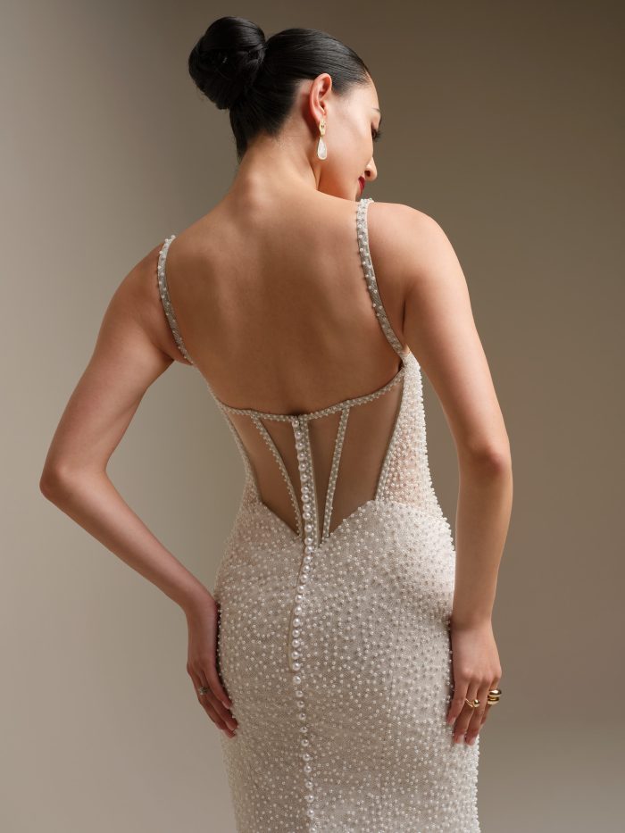 Back view of the Cooper wedding dress showing the plunging illusion V back with glitter tulle corset boning detail, pearl buttons trailing to the hem, and pearl embellished glitter tulle.