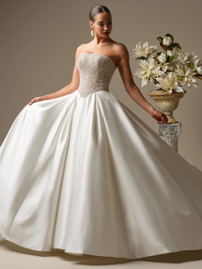 Full-length view of the Dmara ballgown wedding dress by Sottero and Midgley featuring a strapless pearl-embellished bodice and a dramatic full satin skirt with a royal silhouette.