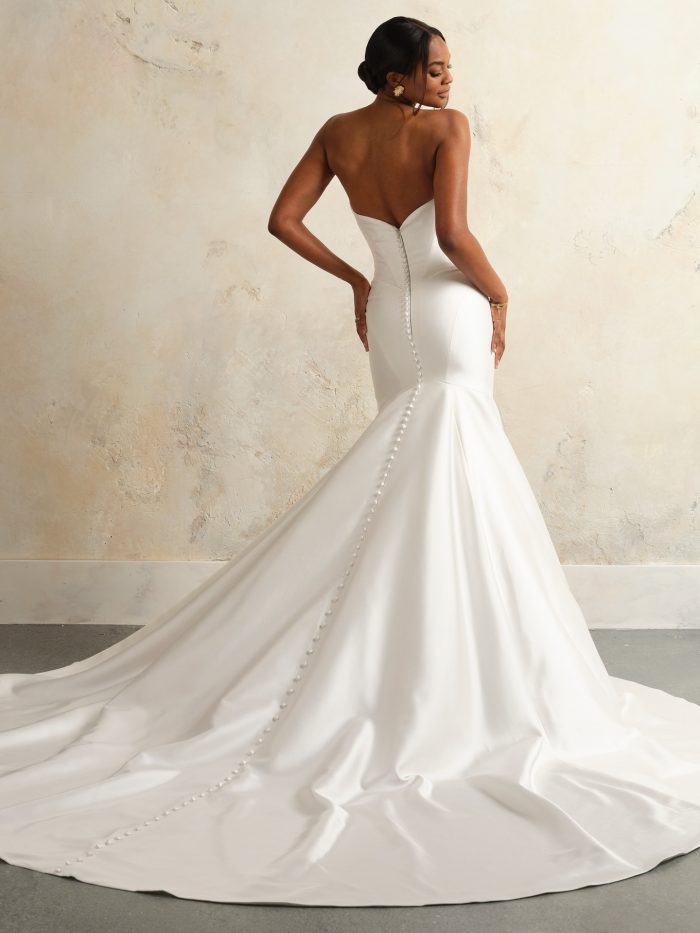 Back view of the Giselle gown showing the row of covered buttons trailing down the fitted silhouette and into the dramatic mermaid train, highlighting the gown’s luxurious satin finish.