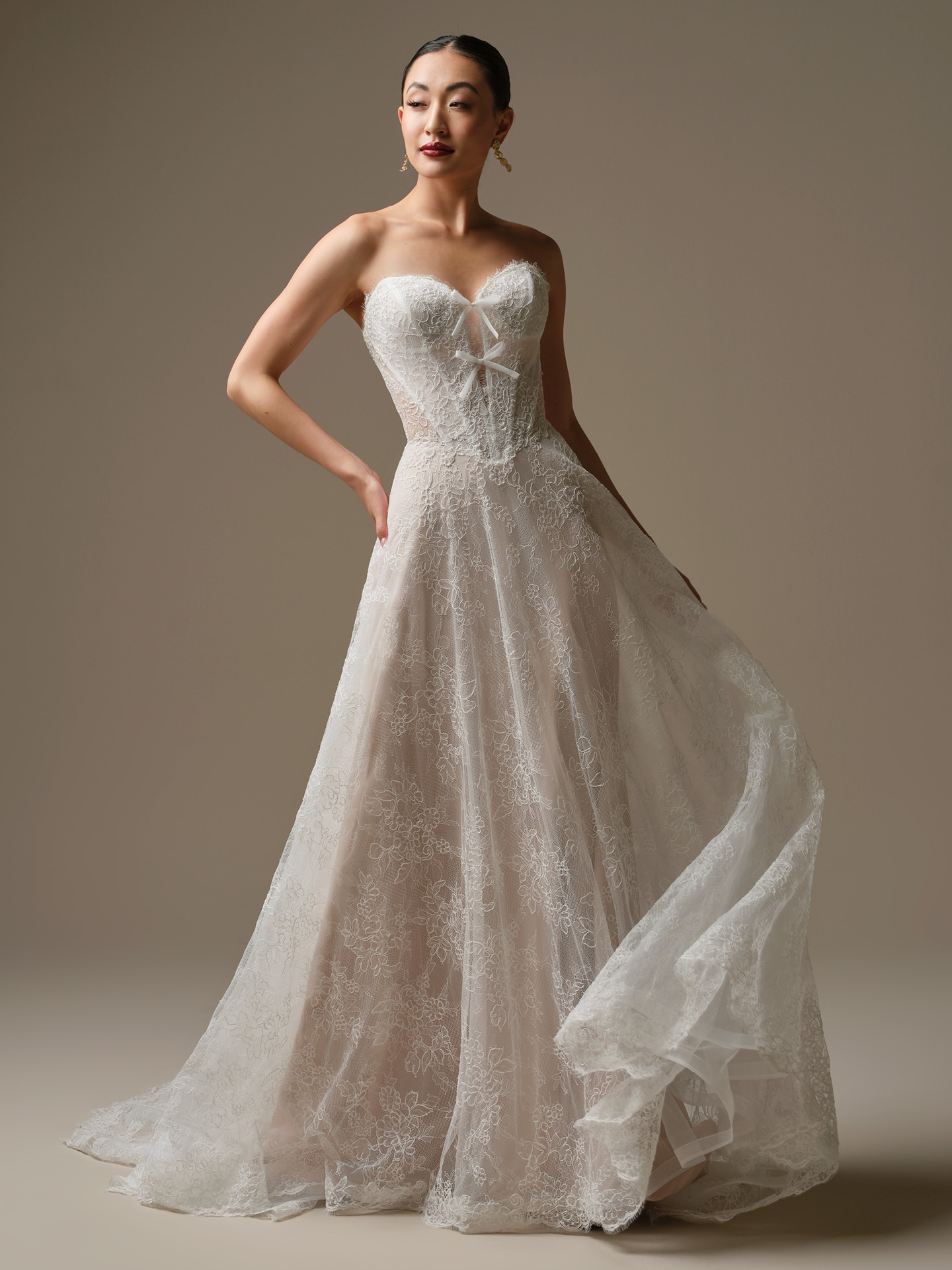 Bride wearing Granger by Sottero and Midgley, an A-line Chantilly lace wedding dress with strapless sweetheart neckline, illusion bodice detail, and flowing lace skirt over blush lining.