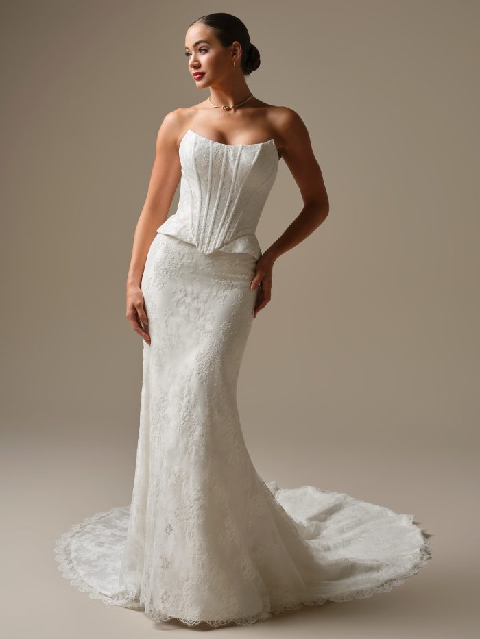 Model wearing the Lassen sheath wedding dress by Sottero and Midgley, featuring a strapless corset bodice, fitted lace silhouette, and elegant lace train.