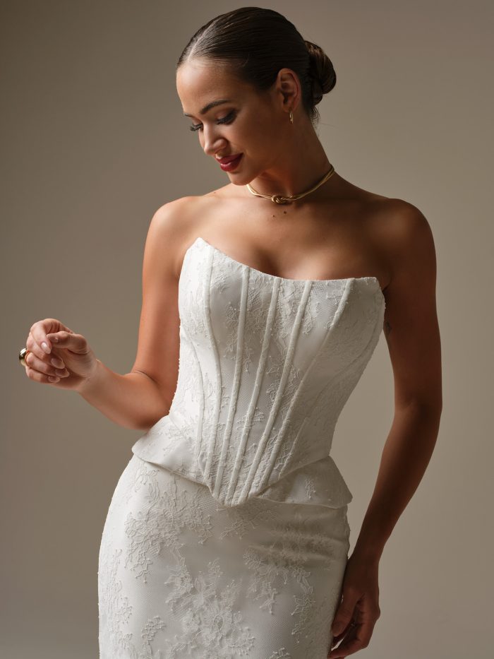 Close up of the Lassen wedding dress showing the structured corset bodice, peplum accents at the hips, and strapless cat eye neckline.