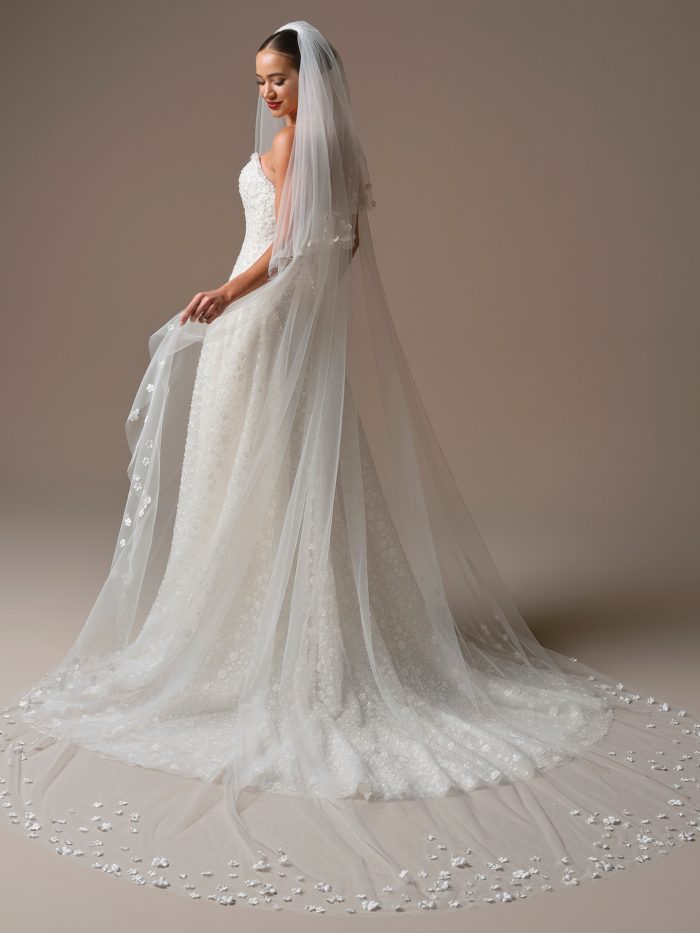 Back view of the Marceline veil by Sottero and Midgley, showcasing its cathedral length, soft tulle layers, and delicate 3D floral motifs trailing along the hem.
