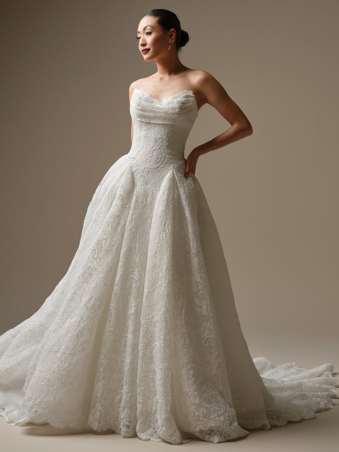 Model wearing the Tamar A-line wedding dress, designed with allover textured lace, a soft sweetheart neckline, and a full pleated skirt for a romantic, classic bridal look.