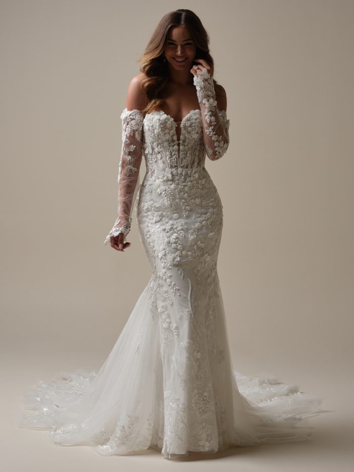 Bride wearing the Sottero and Midgley Twilight fit-and-flare gown featuring a strapless sweetheart neckline with illusion plunge, illusion lace off-the-shoulder sleeves, beaded 3-D floral appliqués over Chantilly lace and glitter tulle, and an extended lace train.