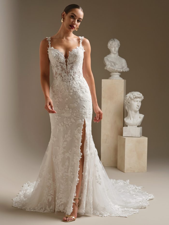 Bride wearing the West fit-and-flare wedding dress featuring beaded lace, an illusion V-neckline, sculpting Basque waist, and a lace train with a thigh-high slit, photographed in a studio setting.